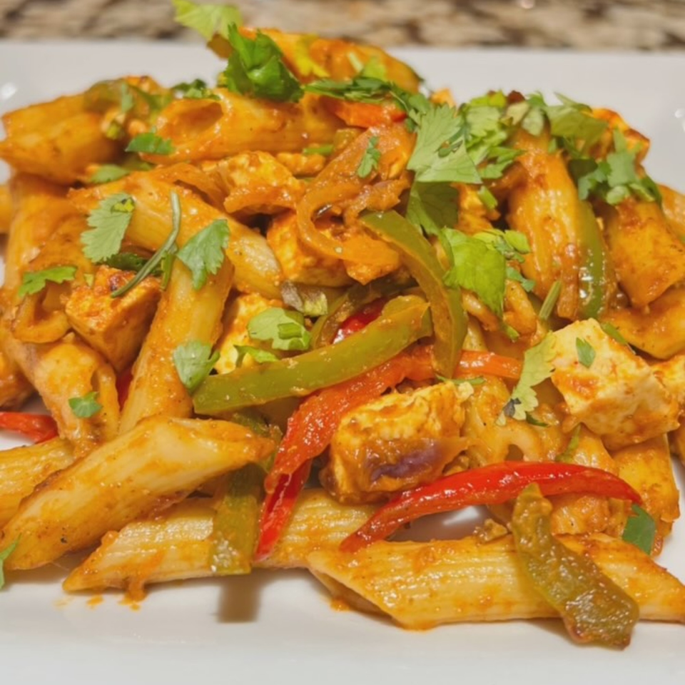 Penne pasta with chicken, bell peppers, and cilantro in a spicy sauce from Slice & Spice.