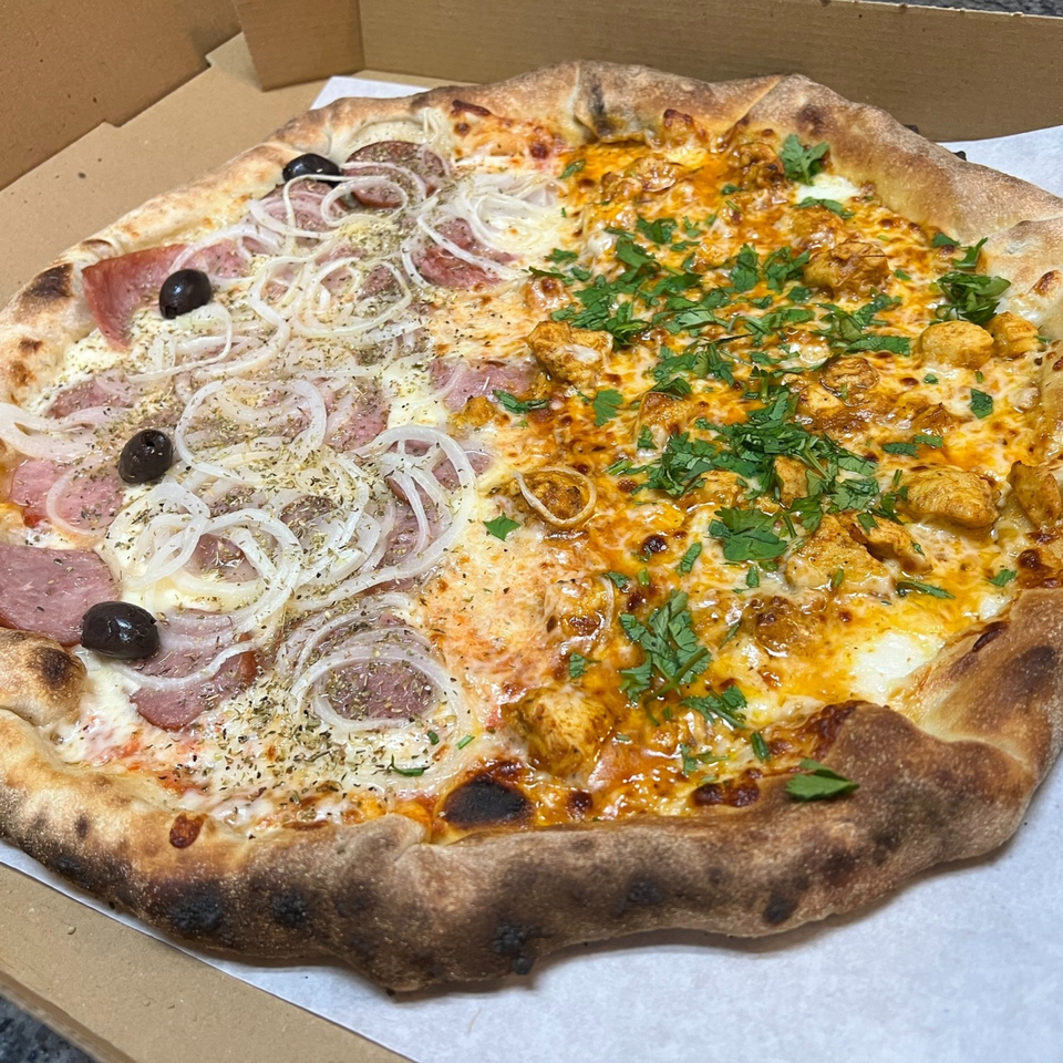 A half-and-half pizza from Slice & Spice, with onions and olives on one side, and chicken with cilantro on the other.